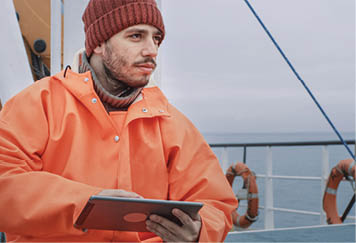Dressed in Protective Coat Fisherman Using Tablet Computer with Navigation Maps while Traveling on Ship 