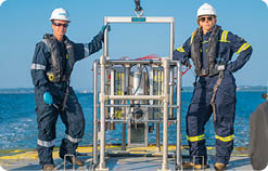 Two people wearing hard hats and life vests. Description generated by AI