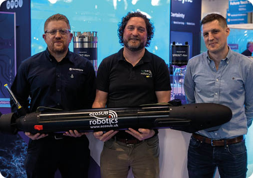 Three men standing in front of a large black object. Description generated by AI