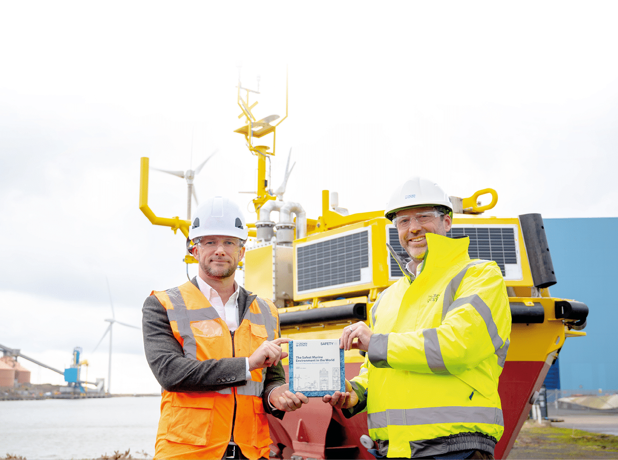 Two men in orange vests are standing in front of a boat. Description generated by AI