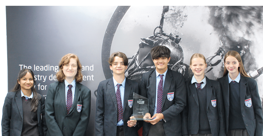 A group of young people in suits and ties are standing in front of a poster. Description generated by AI
